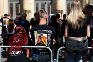 Ein mann mit einem T-shirt in neonazi-Optik und zwei Frauen versammeln sich auf der Straße