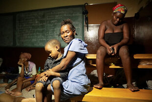 Frauen und Kinder kauern sich auf Bänken im Dunkeln zusammen