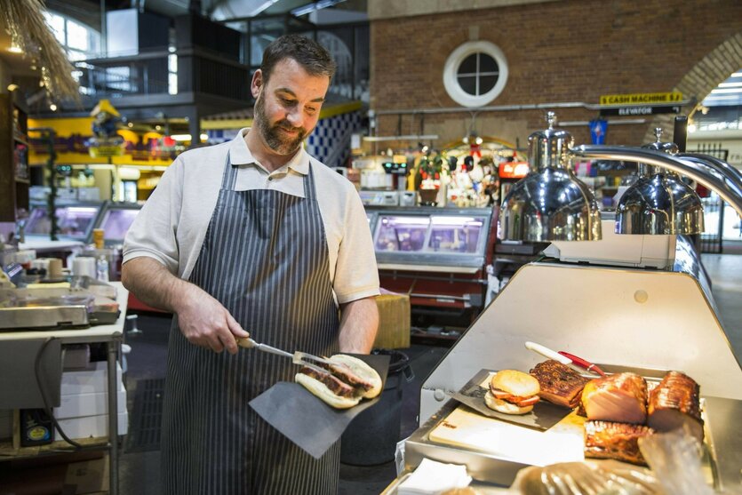 Ein Koch serviert einen Schinken.