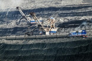 Zwei Kohlebagger, tief im freigelegten Flöz, in den Farben der russischen Flagge, beladen einen Zug