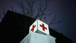 Ein weißer Würfel mit rotem Kreuz vor dunklem Himmel