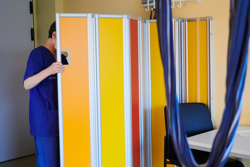 Eine Hebamme verschiebt einen Sichtschutz in einem Krankenhaus