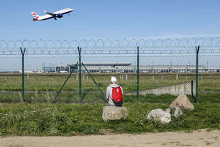 ein Mann schaut zu wie ein Flugzeug abfliegt