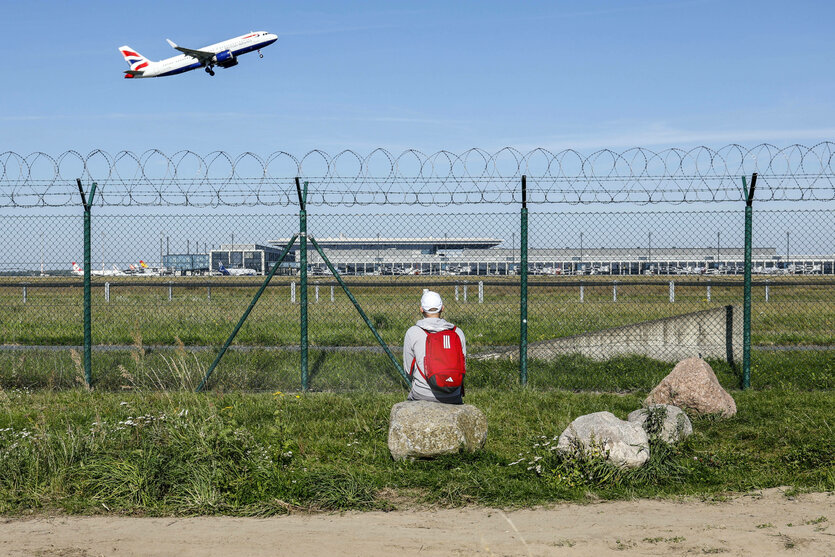 ein Mann schaut zu wie ein Flugzeug abfliegt