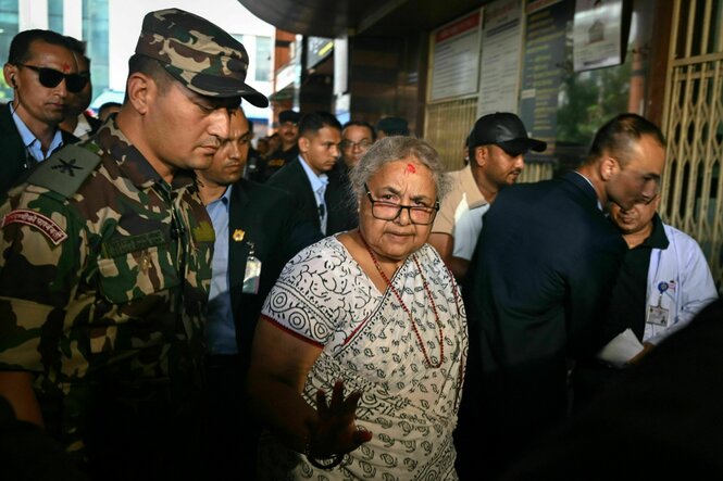 Eine Frau im Sari umringt von Sicherheitspersonal