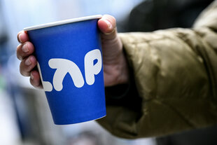 Eine Hand hält einen blauen Pappbecher mit der Aufschrift LAP