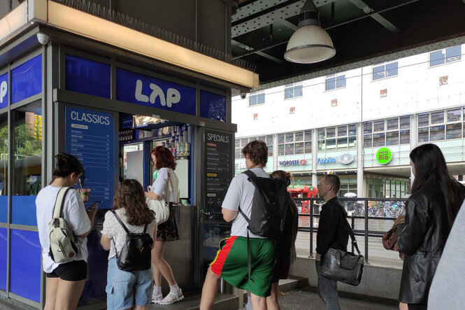 Leute stehen für Kaffee der Kette LAP Coffee an