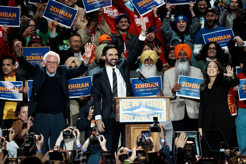 Bernie Sanders, Zohran Mamdani und Alexandria Ocasio-Cortez stehen gemeinsam auf einer Bühne