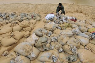 Ein Arbeiter mit großen Säcken, die mit Gesteinsmaterial beladen sind