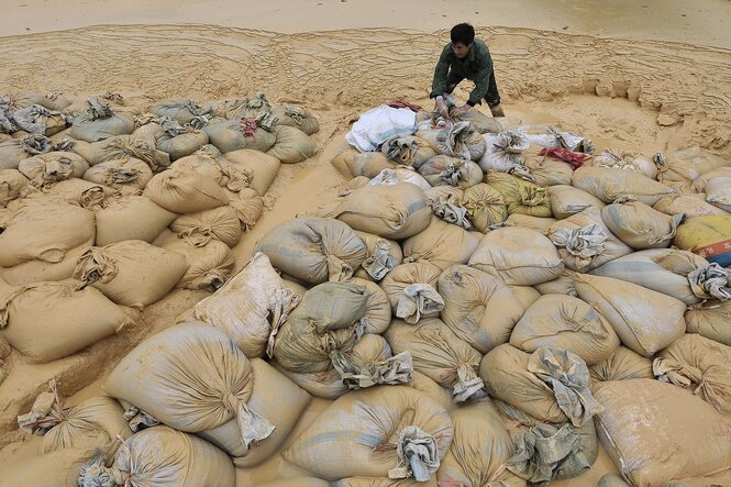 Ein Arbeiter mit großen Säcken, die mit Gesteinsmaterial beladen sind