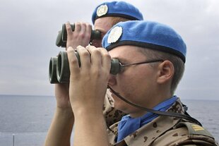 Zwei Soldaten mit blauer Kopfbedeckung blicken durch ihre Ferngläser