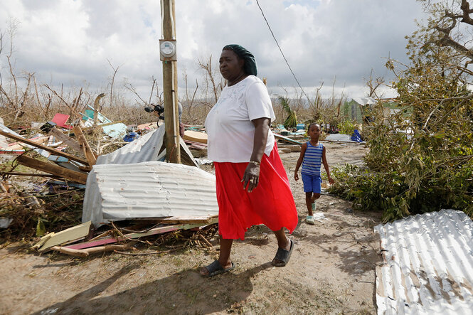 Eine Frau im roten Rock geht durch eine Ruinenlandschaft