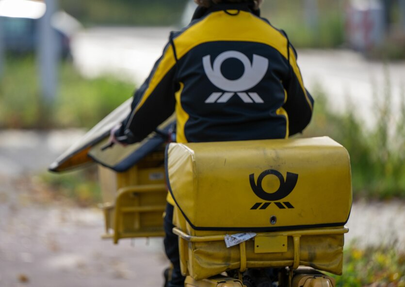 Eine Postbotin in Postkluft auf dem gelben Postrad