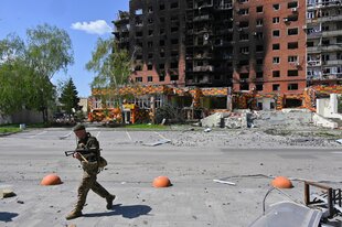 Ein Soldat vor einem ausgebrannten Wohnhaus