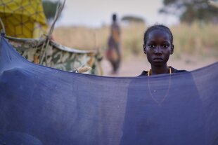 Junge Frau starrt hinter einem Tuch in die Kamera