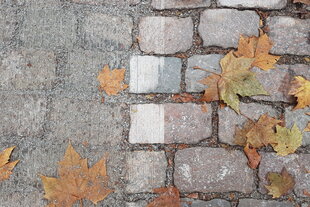 Nahaufnahme von abgeschliffenem Kopfsteinpflaster. Rechts das Original