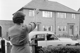 eine Frau winkt einem Mann im Auto zum Abschied