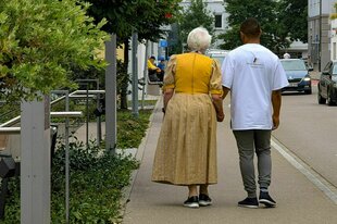 Zwei Personen von hinten laufen nebeneinander auf einem Bürgersteig