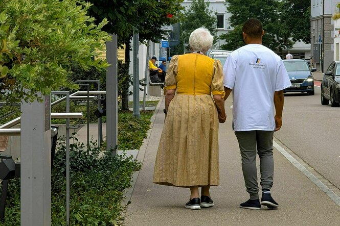 Zwei Personen von hinten laufen nebeneinander auf einem Bürgersteig