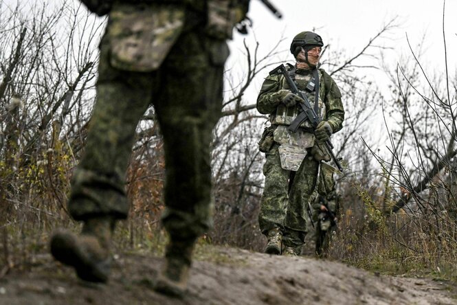 Bewaffnete und vermummte Soldaten laufen hintereinander her
