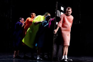 Ein Darsteller hält eine Tür, die anderen stehen dahinter und schieben