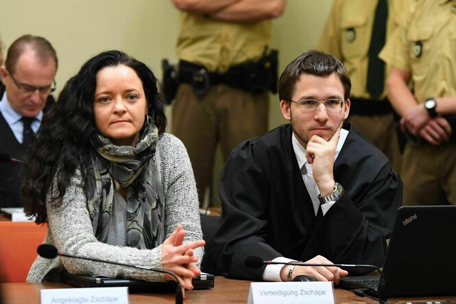 Zwei Personen sitzen in einem Gerichtssaal
