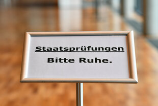 Auf einem Schild in einem Saal mit Holzfußboden steht: 