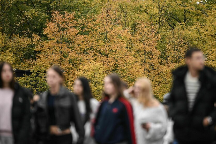 Das Foto zeigt verwischt und unscharf rund ein halbes Dutzend Menschen mit einem Hintergrund herbstlich gefärbter Bäume