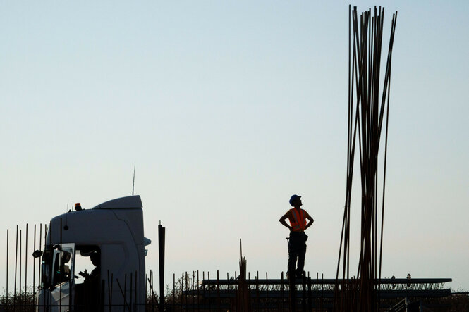 Ein Bauarbeiter auf einem Laster neben einer Baustelle
