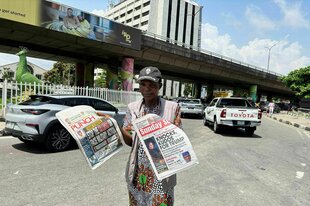Ein zeitungsverkäufer steht auf einer befahrenen Straße