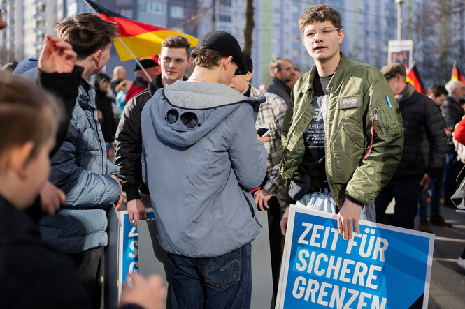 Eine Gruppe Jugendlicher demonstriert mit Deutschlandfahnen und Plakaten der AFD