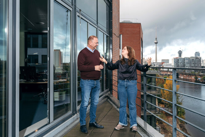 Ricarda Lang und Frank Werneke stehen gut gelaunt auf der Terrasse im Verdi-Haus Berlin, im Hintergrund die Skyline von Berlin mit Fernsehturm