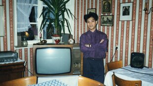 Eine Person in einem Zimmer mit Fernseher, altes Foto.