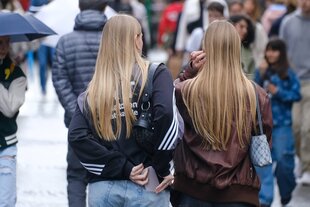 Zwei junge Frauen, eine steckt ein Smartphone in die Hosentasche