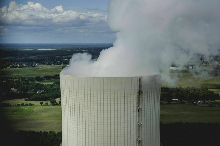 Dichter Rauch quillt aus einem Kühlturm und verdeckt dabei eine schöne Landschaft