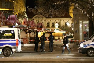 Einsatzfahrzeuge der Polizei stehen vor dem Weihnachtsmarkt in Magdeburg.