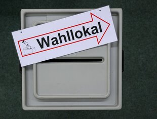 Das Bild zegt den Einwurfschlitz einer Wahlurne, auf der ein Schild mit der Aufschrift 