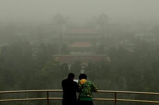 Zwei Personen vor einem smogverhangenen Panorama