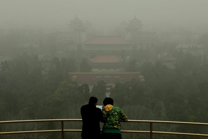 Zwei Personen vor einem smogverhangenen Panorama