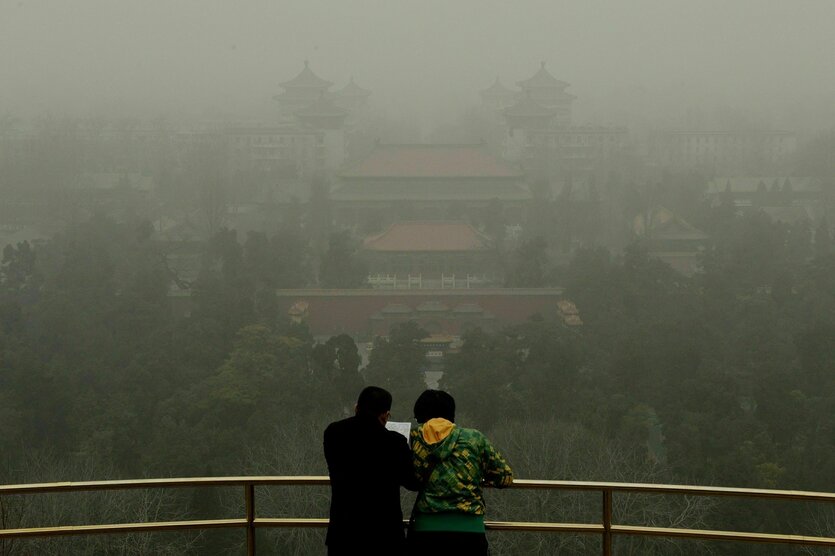 Zwei Personen vor einem smogverhangenen Panorama