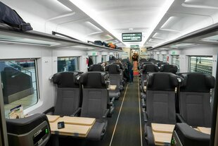 Innenansicht eines Abteils der dänischen Staatsbahn, graue Sitze, wrikt geräumig, wenig Reisende im Zug