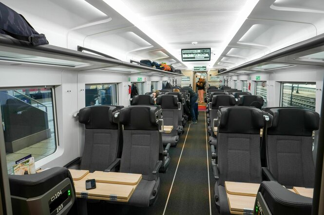 Innenansicht eines Abteils der dänischen Staatsbahn, graue Sitze, wrikt geräumig, wenig Reisende im Zug