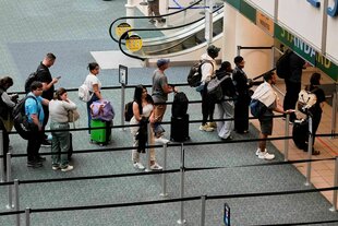 Reisende stehen am Flughafen Orlando in Florida zur Sicherheitskontrolle Schlange