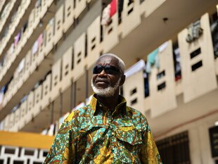 Ein Mann mit Sonnenbrille und buntem Hemd vor einer Häuserwand