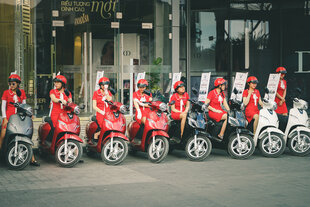 Rot-gekleidete Hostessen auf sitzen auf VinFast-Motorrollern