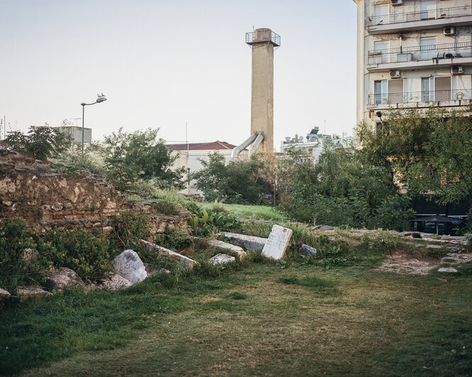 Steine auf einer Wiese, im Hintergrund ein Schornstein.