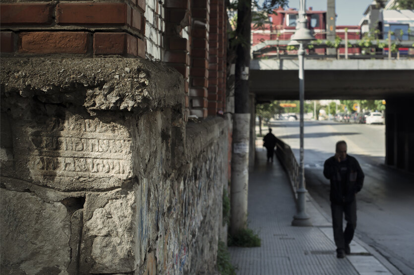 Eine Mauer, im Hintergrund eine Brücke.