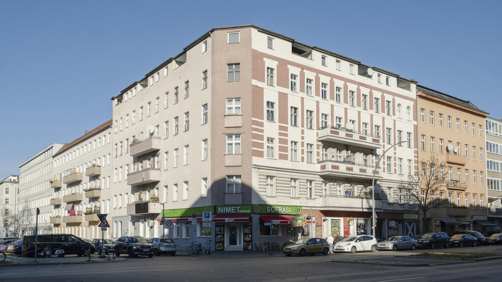 Ein großes Mietshaus an einer Straße.