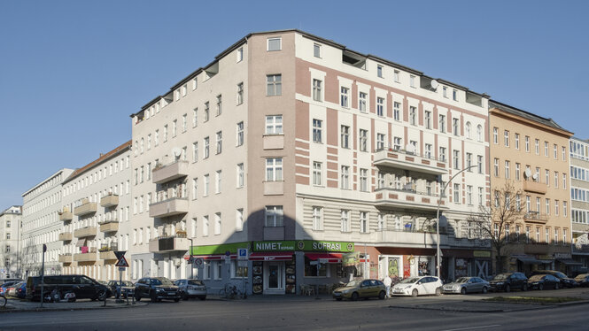 Ein großes Mietshaus an einer Straße.