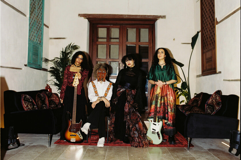 Die Band Seera steht zwischen Sofas vor einem Haus